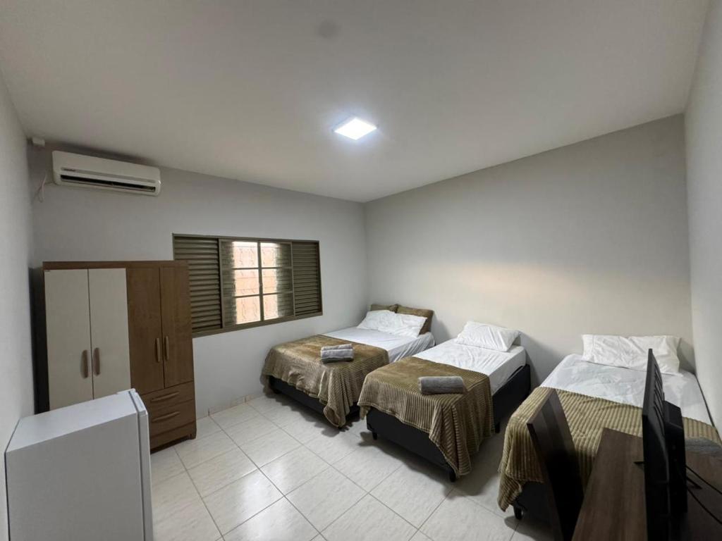 a hotel room with two beds and a window at Alvorada Hospedagem in Jataí