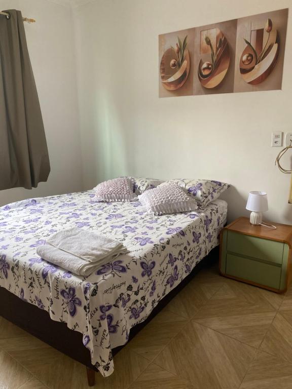 a bedroom with a bed with a purple and white comforter at Casa dá Jo in Rio das Ostras