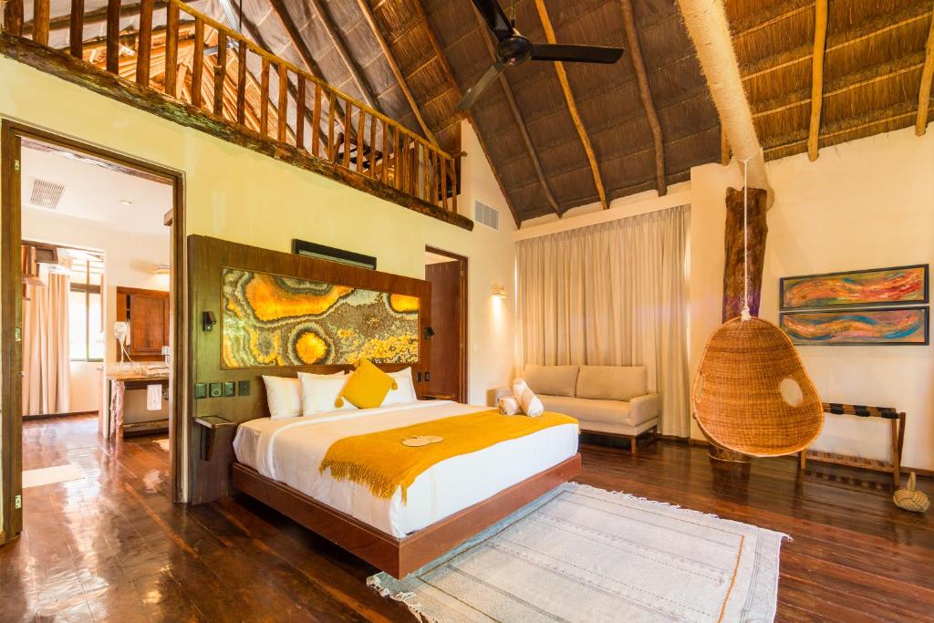 a bedroom with a bed and a chair in a room at Casa Teka - Boutique Hotel & Cenote in Tulum