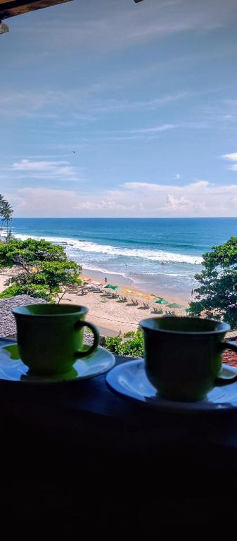 two cups on a table with a view of the beach at MistiHouse Surf & Amor con vista al mar a 50 mts de la playa in Itacaré