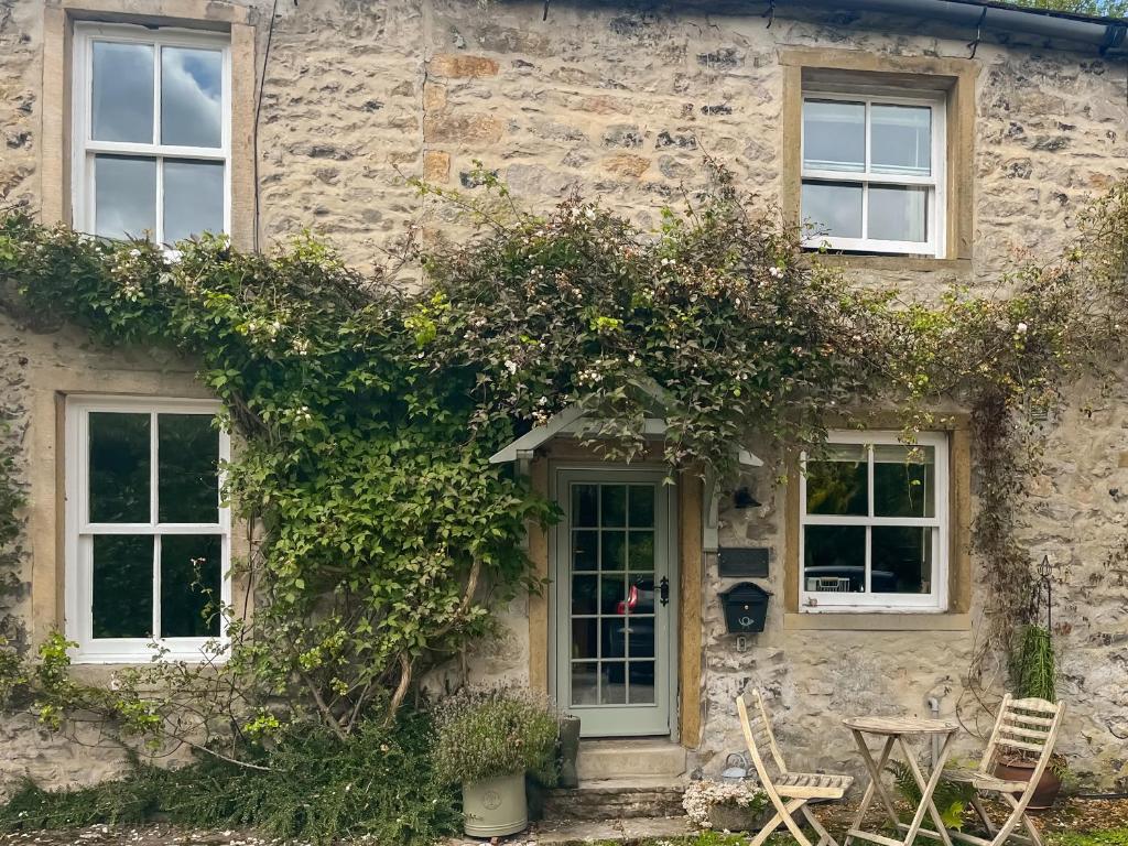 a stone house with ivy on the side of it at Granary Cottage in Kirkby Malham