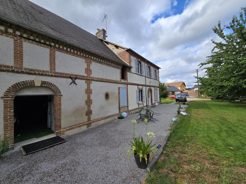 a brick building with a garage next to a yard at La Hacienda Verde in Heudreville-sur-Eure