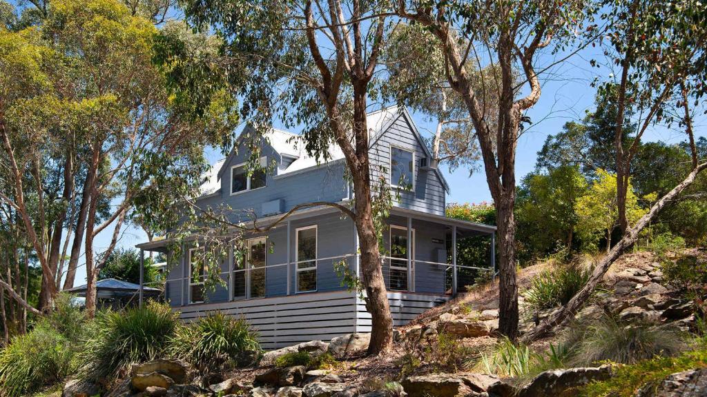 a white house on a hill with trees at Kingfisher Loft in Daylesford