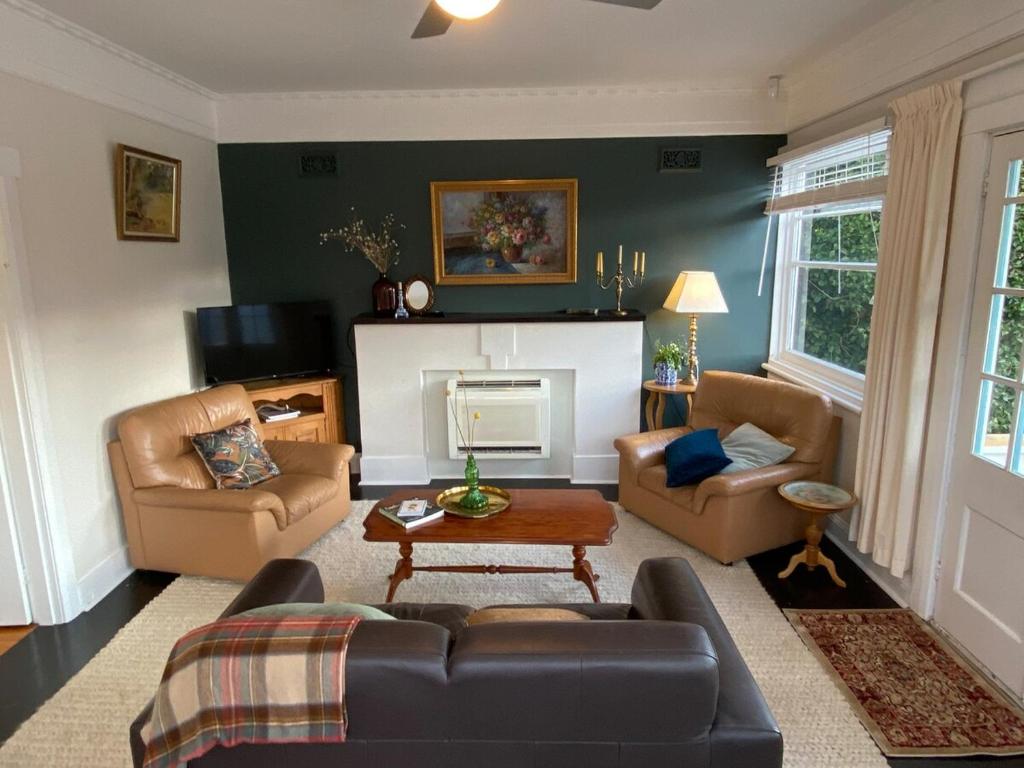 a living room with a couch and chairs and a fireplace at Whimsy Cottage, Beachside retreat, Outdoor bath in Kingston Beach