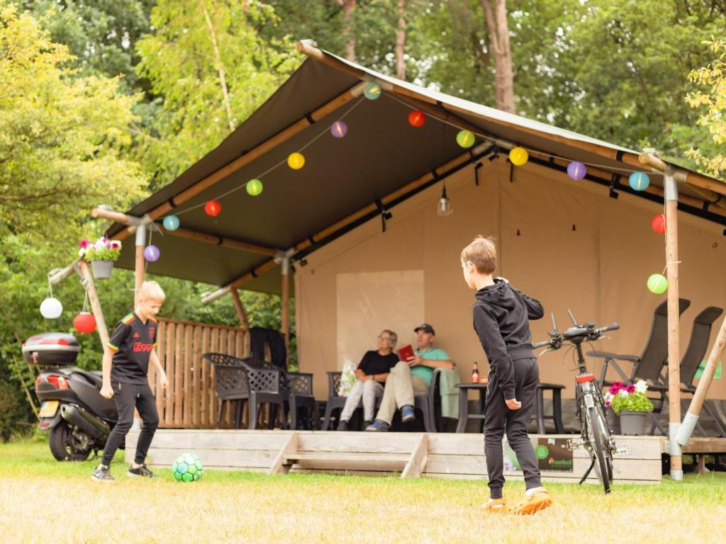 two boys playing with a soccer ball in front of a tent at De Hommel in Hulshorst