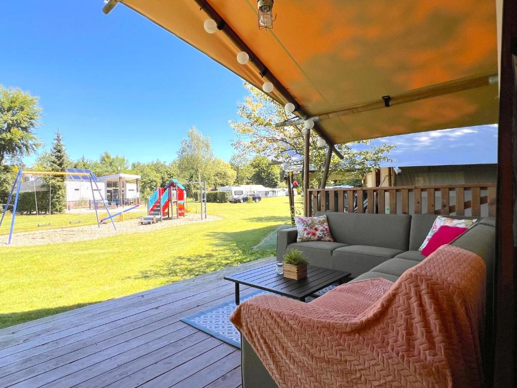 a patio with a couch and a table and a playground at de Krekel in Hulshorst