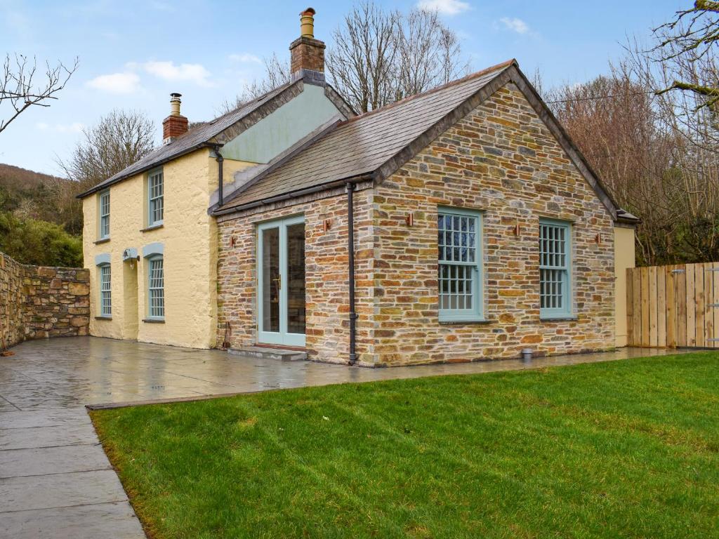 a brick house with a green lawn in front of it at Bluebell Cottage in Bodmin
