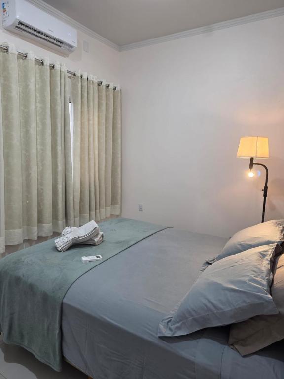 a bedroom with a large bed with a lamp and curtains at Apartamento Aconchegante 103 Palmeiras de Goiás in Palmeiras de Goiás