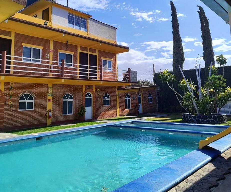 a house with a swimming pool in front of it at Hotel y Cabañas Quinta Los Cipreses in Atlatlahucan