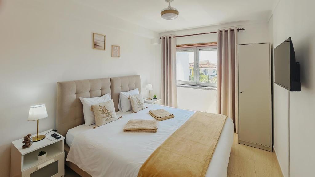 a bedroom with a large white bed with a window at Baleal Beach Stay in Baleal