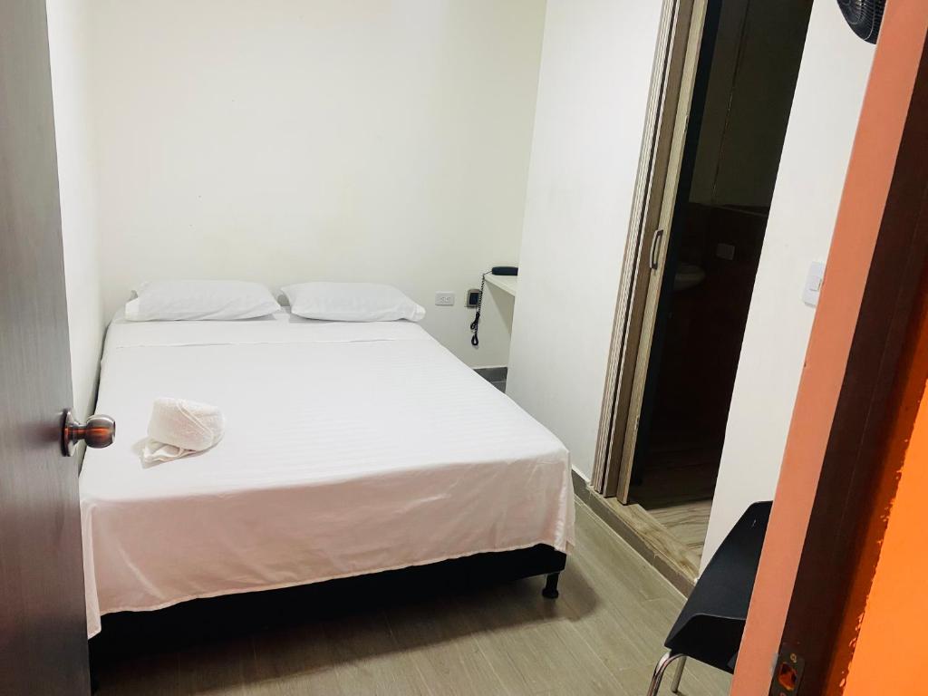 a white bed in a small room with a door at Hotel sahara in Medellín