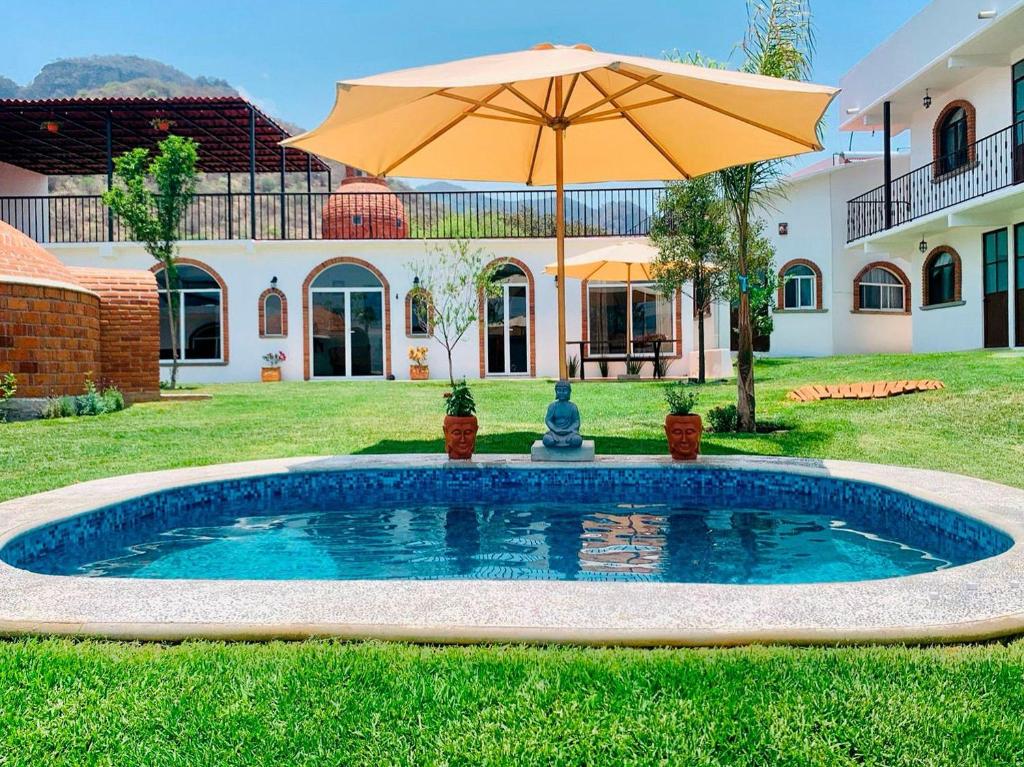 a pool in the yard of a house with an umbrella at Casa AmaNacer Malinalco in La Ladrillera