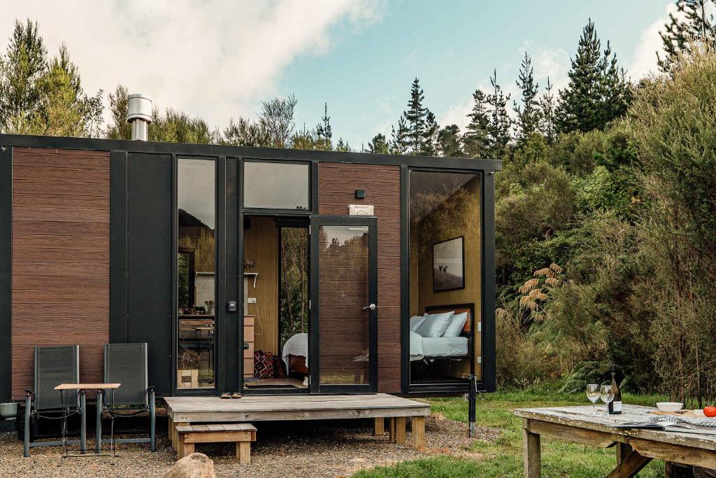 a small black house with a picnic table at Te Paki Dam View X by Tiny Away in Sanson
