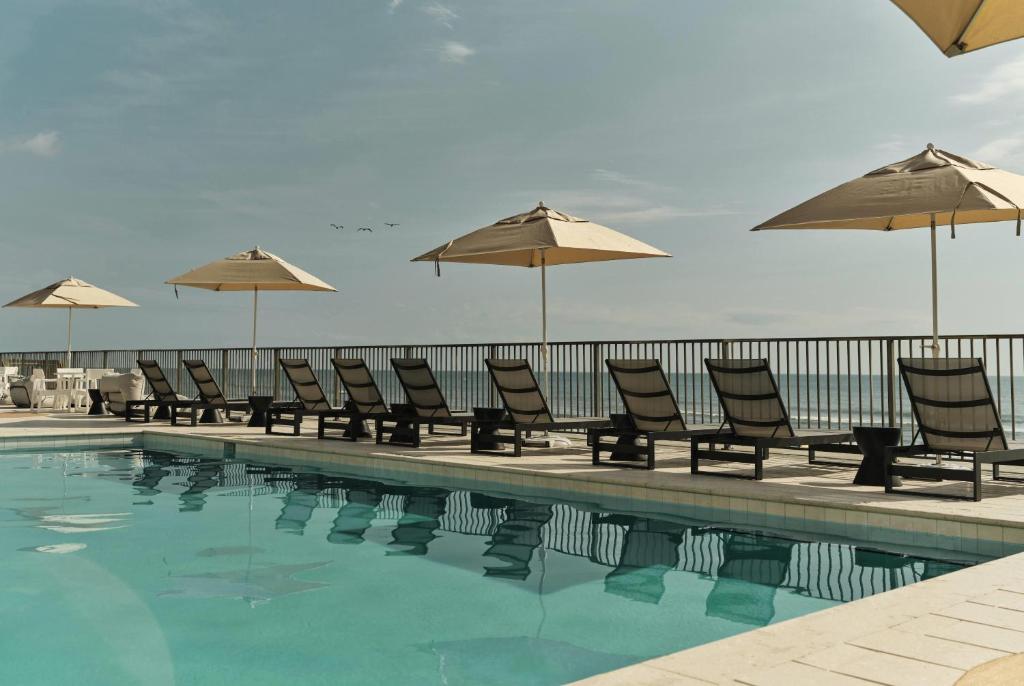 a row of chairs and umbrellas next to a swimming pool at Ambros Daytona, Trademark Collection by Wyndham in Daytona Beach