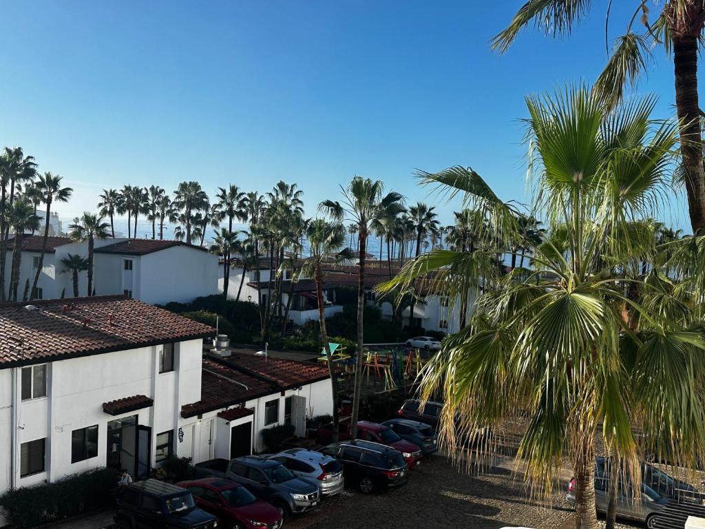 a group of cars parked in a parking lot with palm trees at La Paloma in Rosarito Beach