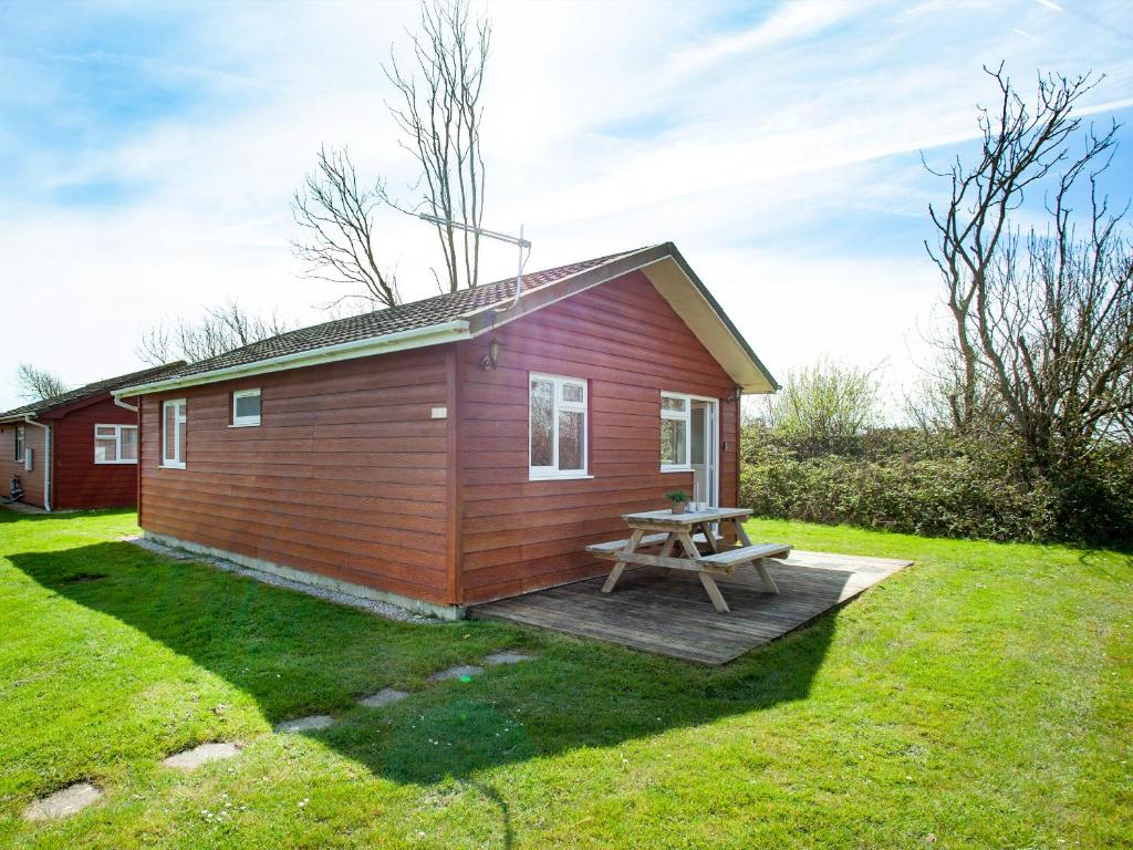 a small red cabin with a picnic table in a yard at Lodge 133 - Uk43196 in Saint Merryn