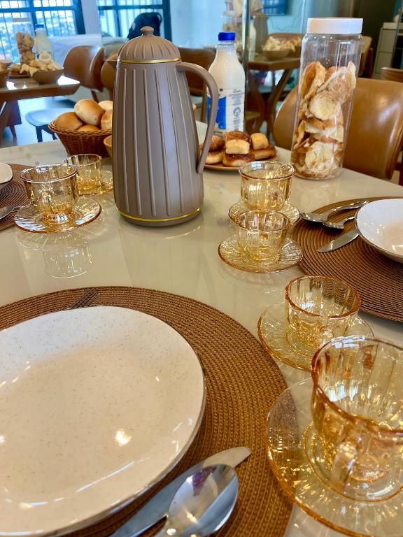 a table with plates and glasses and bread on it at Azure Aesse Hospitality Marista in Goiânia