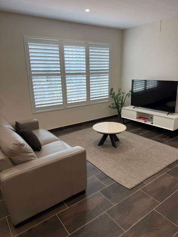 a living room with a couch and a flat screen tv at Belmore Living in Goulburn