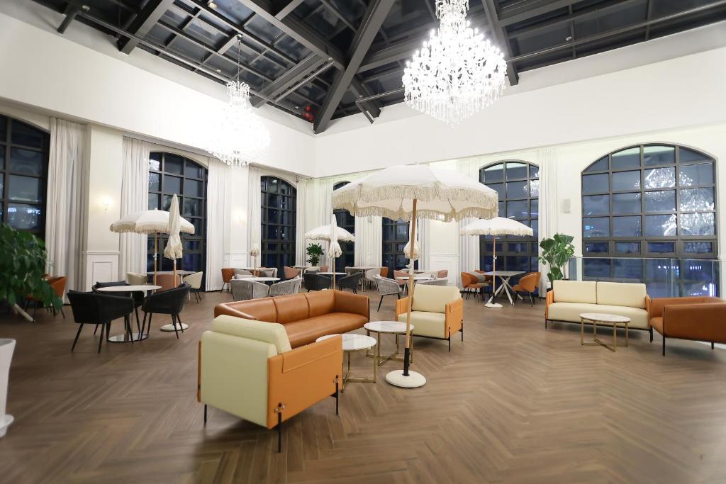 eine Lobby mit Sofas, Tischen und Fenstern in der Unterkunft 루나스카이돔 구 스페이스앤무드 in Busan