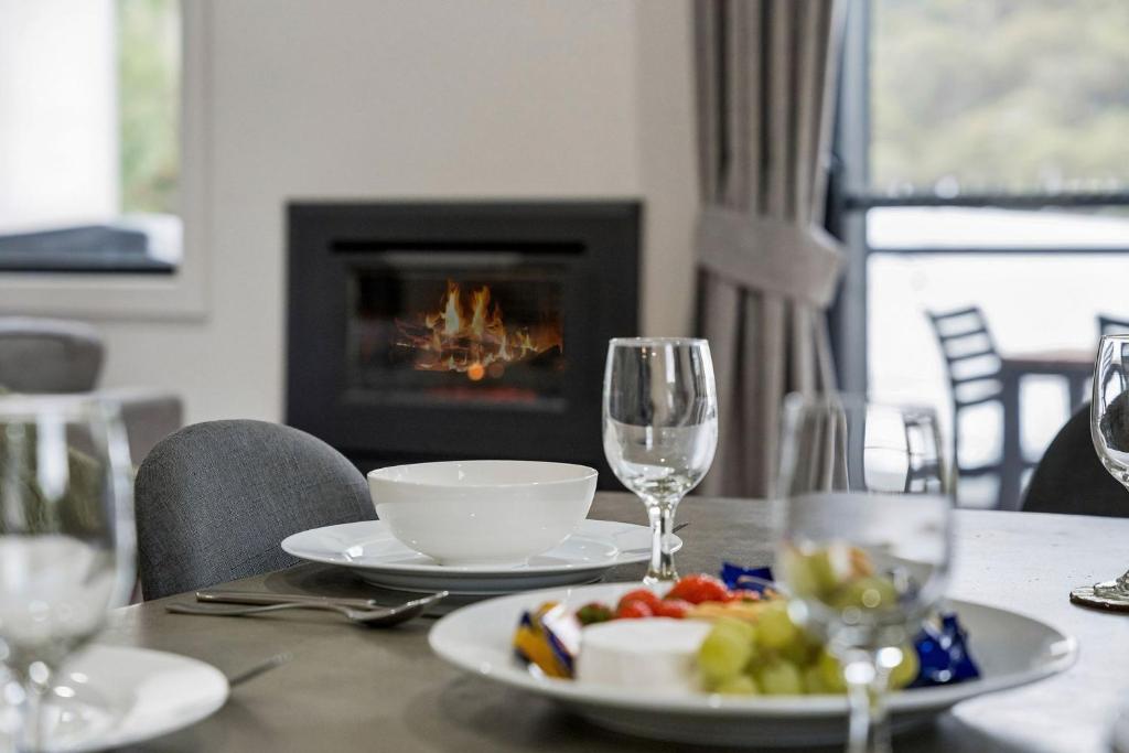 a table with a plate of food and wine glasses at Roses Creek Chalet B in Crackenback