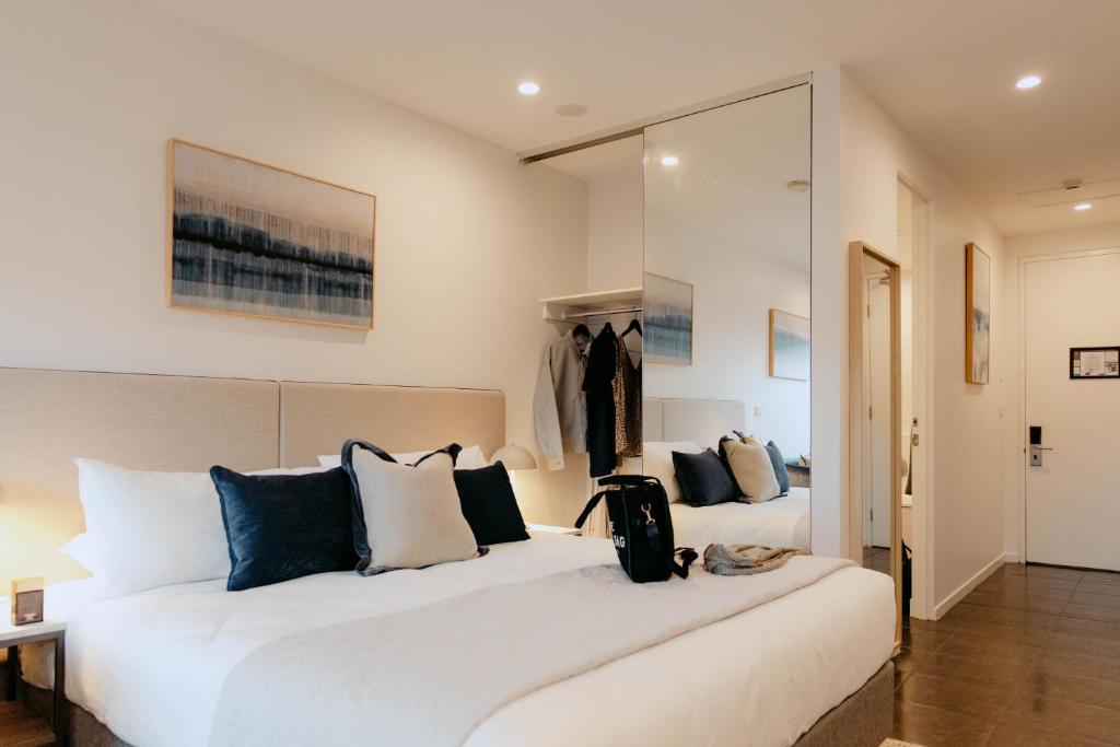 a bedroom with a large white bed with blue pillows at Punthill Williamstown in Williamstown