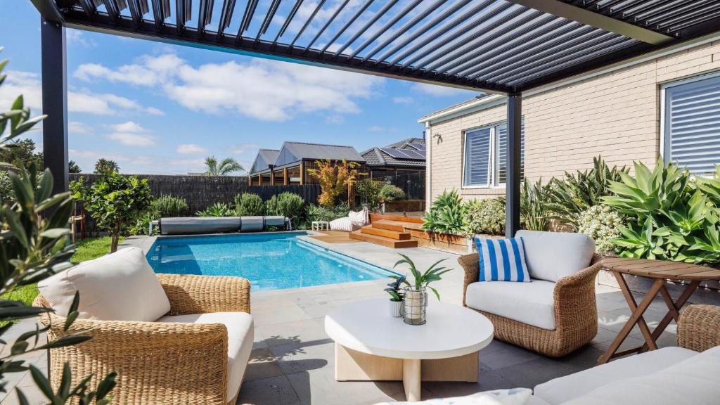 a patio with a pool and chairs and a table at Secret Haven in Safety Beach