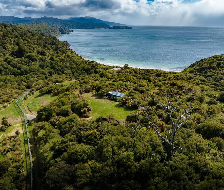 an aerial view of a house on a hill next to the ocean at Hananui PurePod in Stewart Island