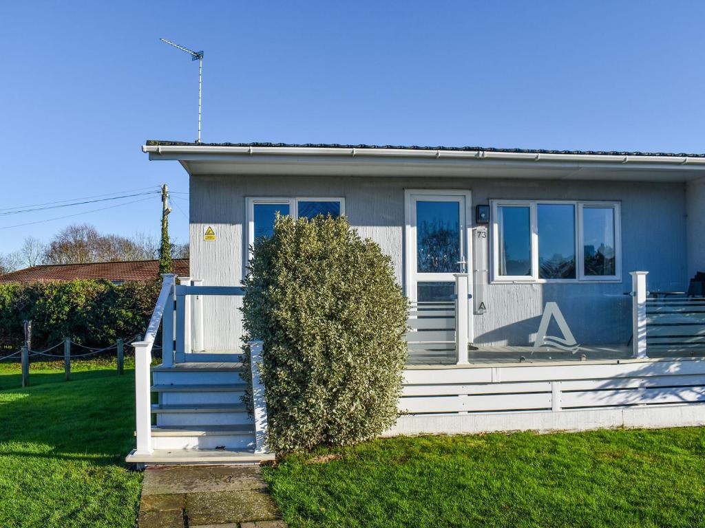 a blue house with a white door and a hedge at Alula Lodge in Lowestoft