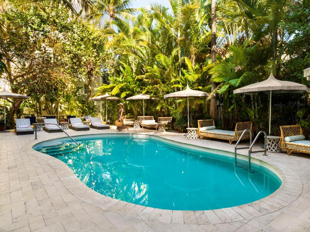 a swimming pool with chairs and umbrellas in a resort at Hotel Trouvail Miami Beach in Miami Beach