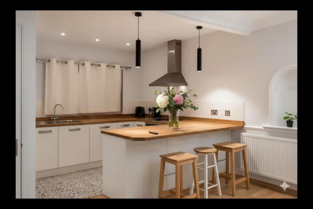 a kitchen with white cabinets and a counter with stools at Peasehill StMichaels in Rawdon