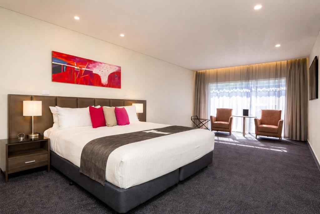 a hotel room with a large bed and two chairs at Alexandra Hills Hotel in Cleveland