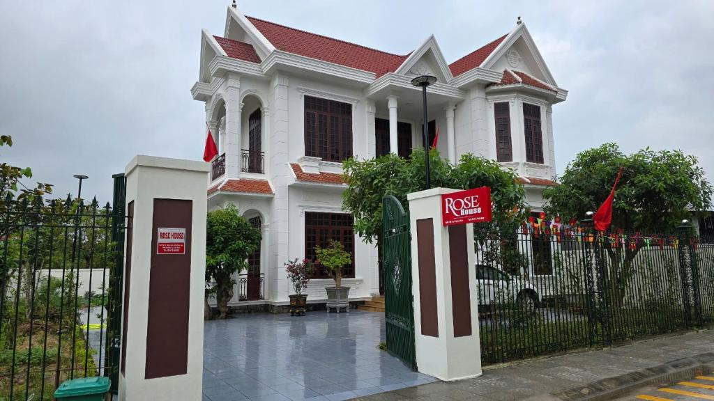 a large white house with a gate and a fence at Rose House - Quảng Bình in Bố Trạch