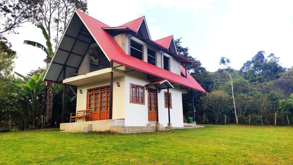a small house with a red roof on a field at Cabaña Monte Santo in Oxapampa