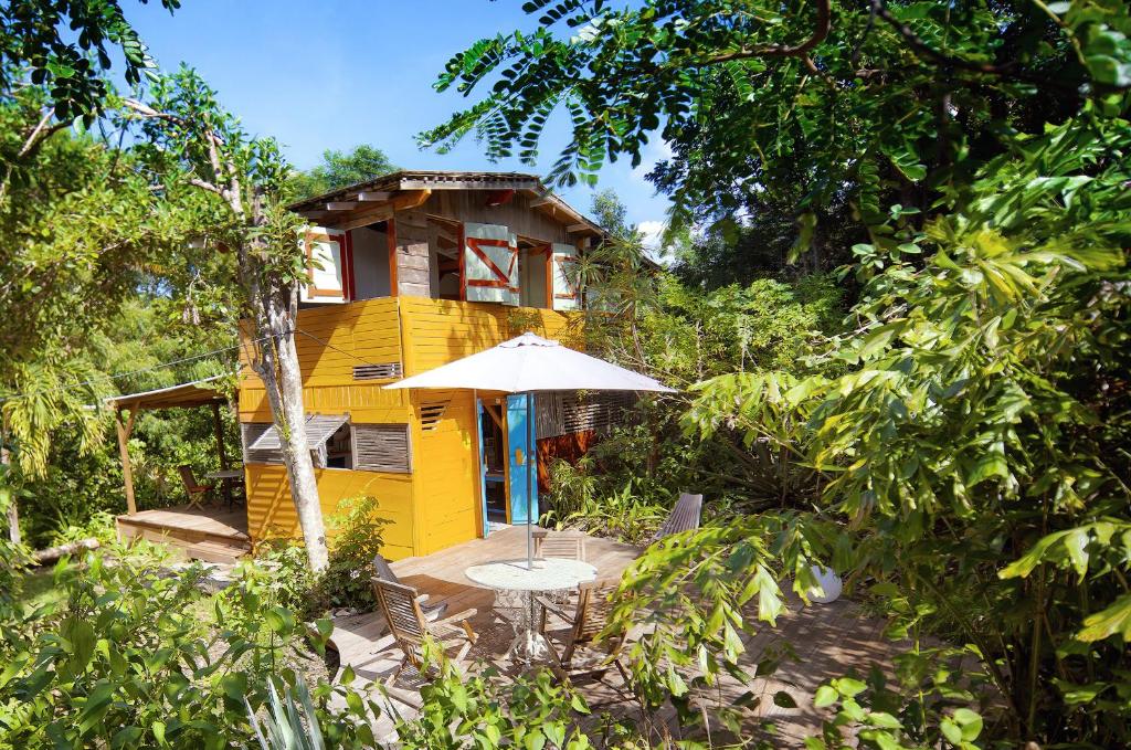 a yellow house with a table and an umbrella at Esprit Caraibe in Saint-François