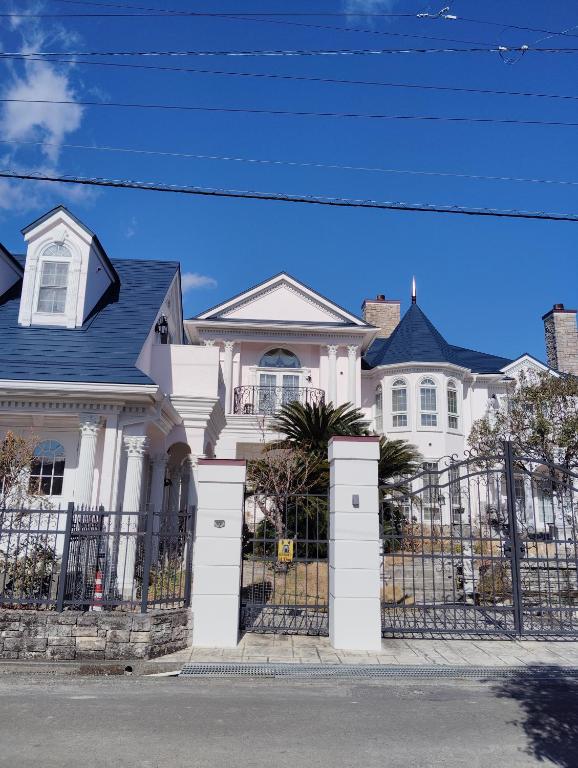 a white house with a gate and a fence at シンデレラ城風 邸宅のゲストハウス民泊 in Tosa