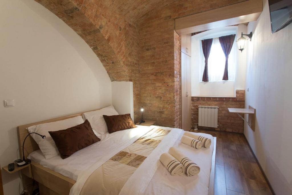 a bedroom with a white bed with a brick wall at Guesthouse BED 4 YOU in Zagreb
