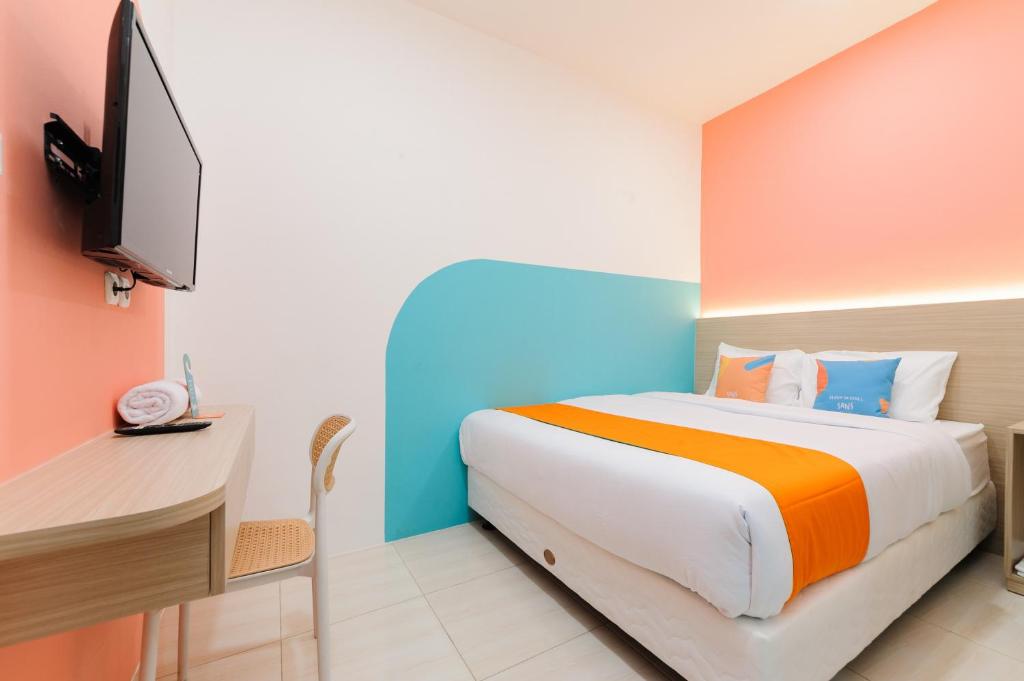 a bedroom with a bed and a desk and a tv at Sans Hotel Cengkareng in Jakarta