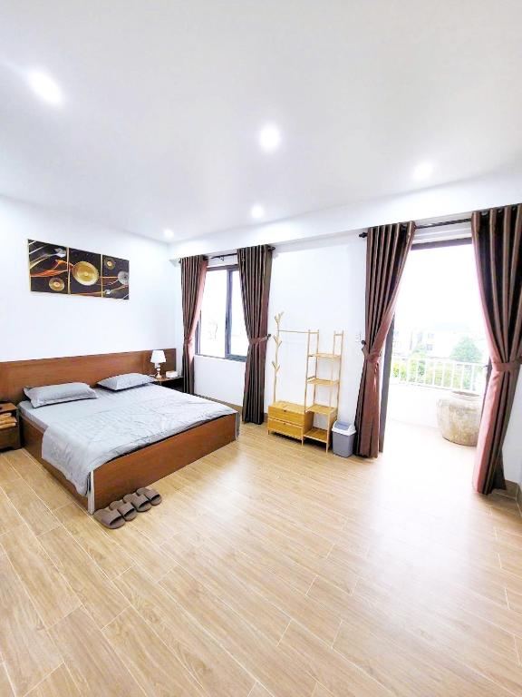a bedroom with a bed and large windows at Fullhouse Riverside Homestay in Hue