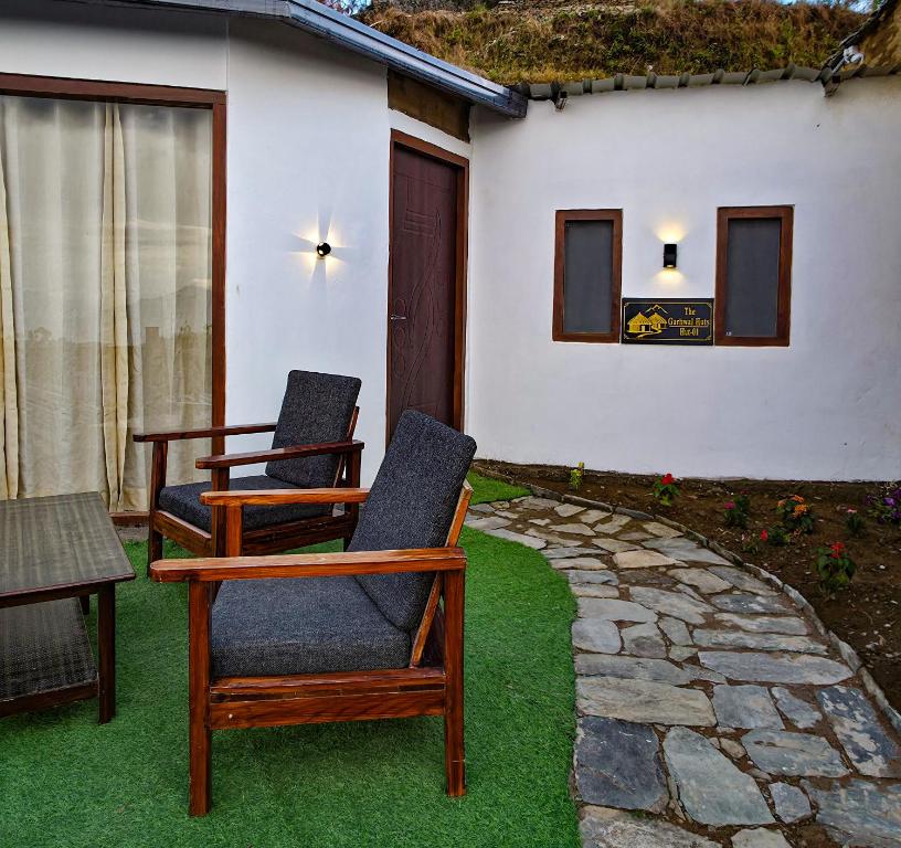 two chairs sitting on a lawn in front of a house at The Garhwal Huts in Pauri