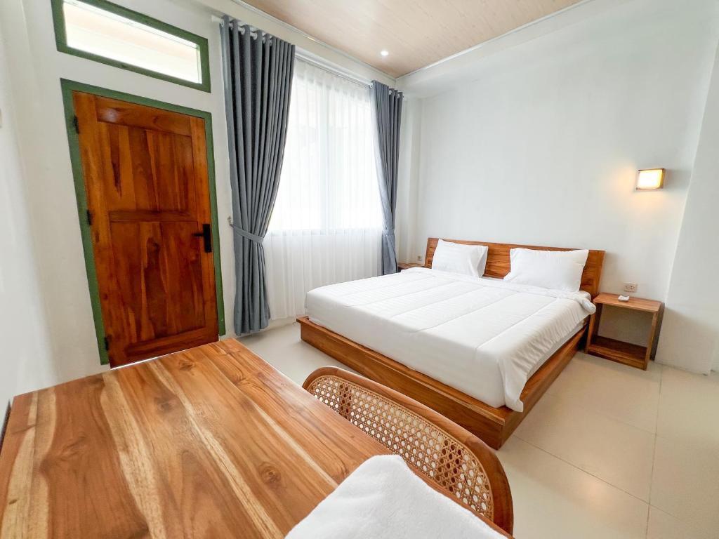 a bedroom with two beds and a wooden table at La Casa de Maria in Komodo Labuan Bajo Airport