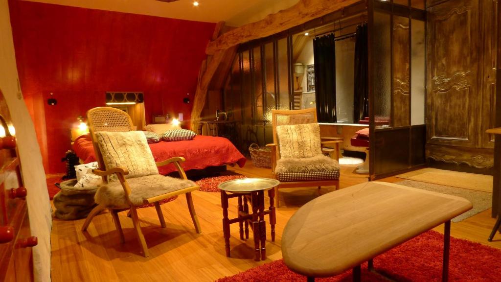 a bedroom with a bed and two chairs and a table at Les Insolites de Coco in La Lande-de-Goult