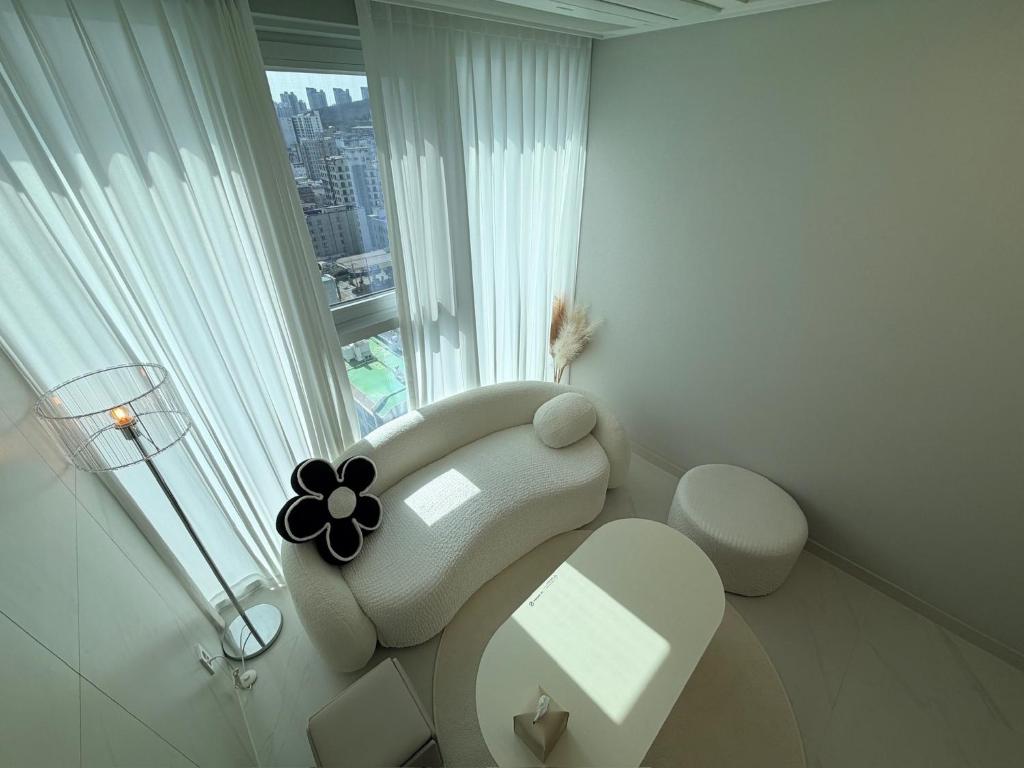 a white living room with a chair and a window at 해변1분 숙소 광안이즘, 1 min to beach Gwangan-ism in Kwangan-dong