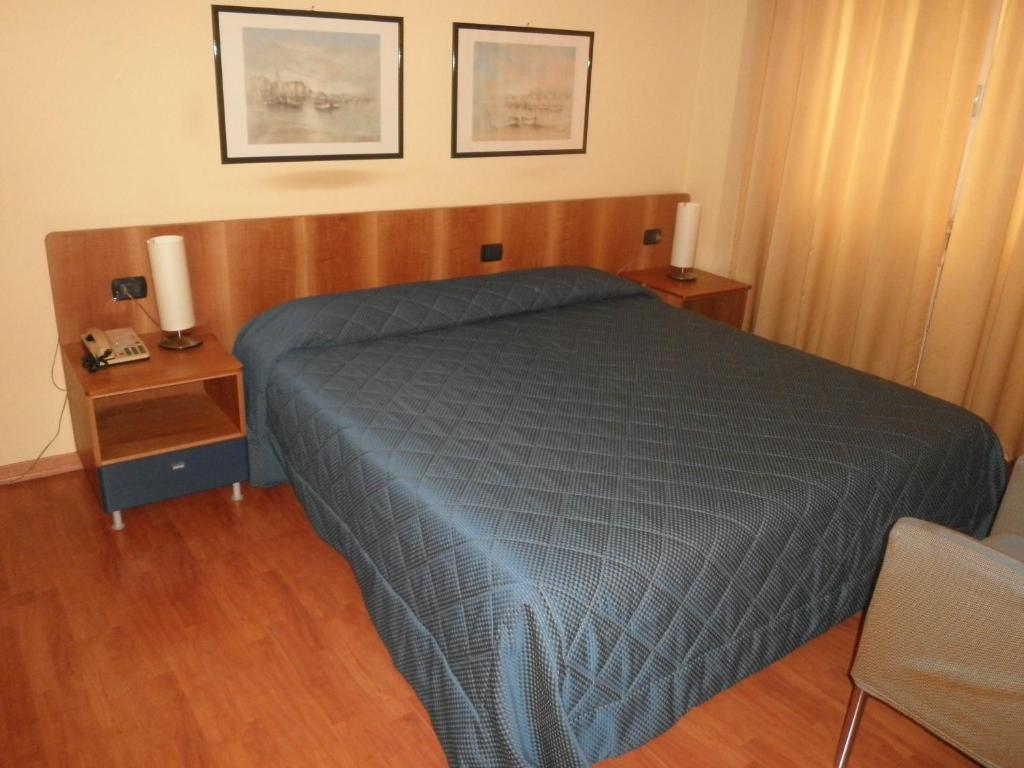 a bedroom with a bed with a blue comforter at Hotel Selide in Desio