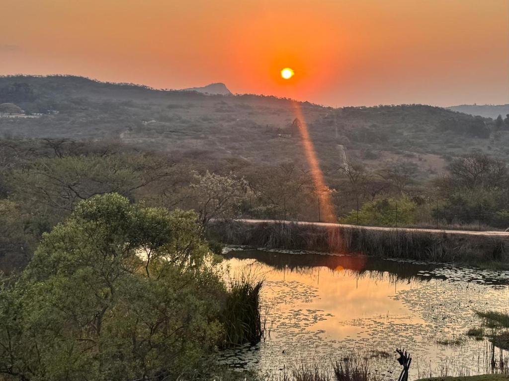 a sunset over a river with a rainbow at Syeta Bush Lodge - Bush Serenity in Nelspruit
