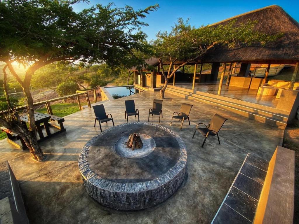 an outdoor patio with a fire pit and chairs at Syeta Bush Lodge - Sunset View in Nelspruit
