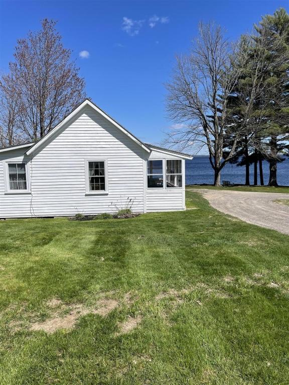 a white house sitting on top of a grass field at THE SHOPPE LIMIT 3 cabin in North Sebago