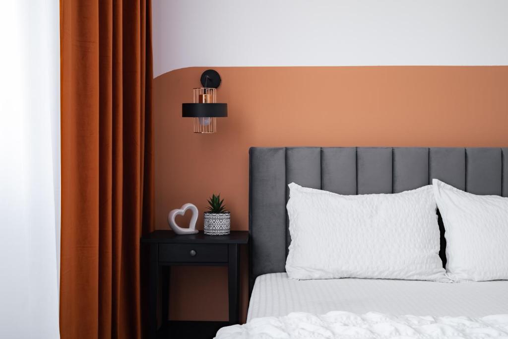 a bed with a gray headboard next to a side table at Sika Platinum Apartment - cazare premium Arad - self check-in in Arad