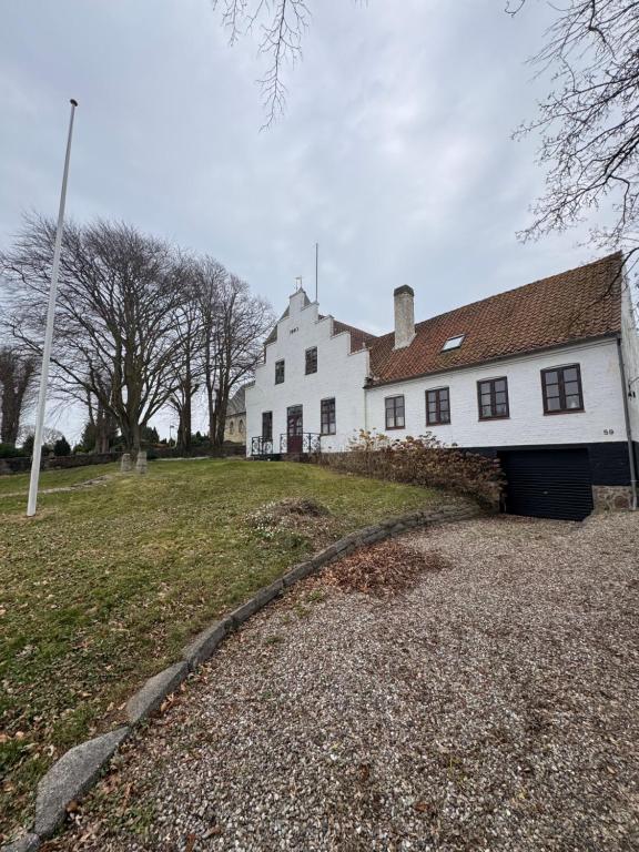 a white house with a garage in front of it at Skelby Præstegård lej 1 in Gedser