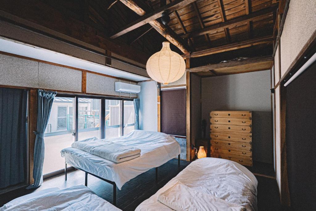 a bedroom with two beds and a window at 松本市の静謐と温もりあふれる隠れ家邸宅 in Matsumoto