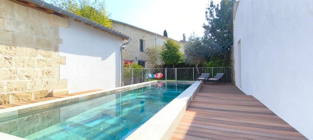 a swimming pool with a wooden deck and a house at La Grange de Junas in Junas